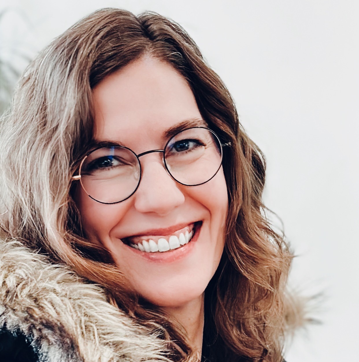 Profile photo of Rachel Pursell smiling, with fair skin, round glasses, and wavy brown hair