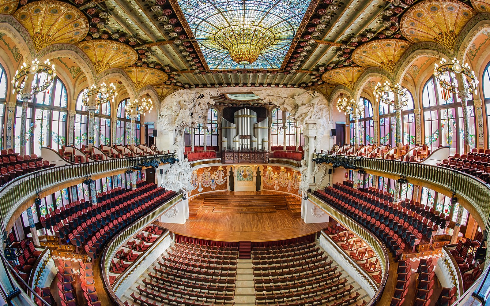 Wnętrze sali koncertowej Palau de la Musica Catalana w Barcelonie, prezentujące ozdobną architekturę i żywe witraże.