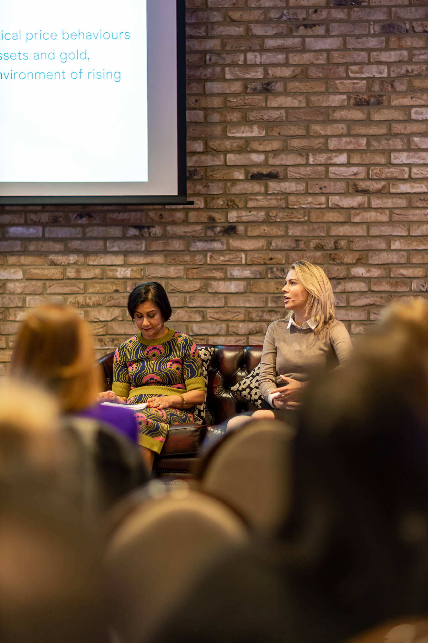 Women speaking during a finance event panel discussion in front of a live audience at a business conference