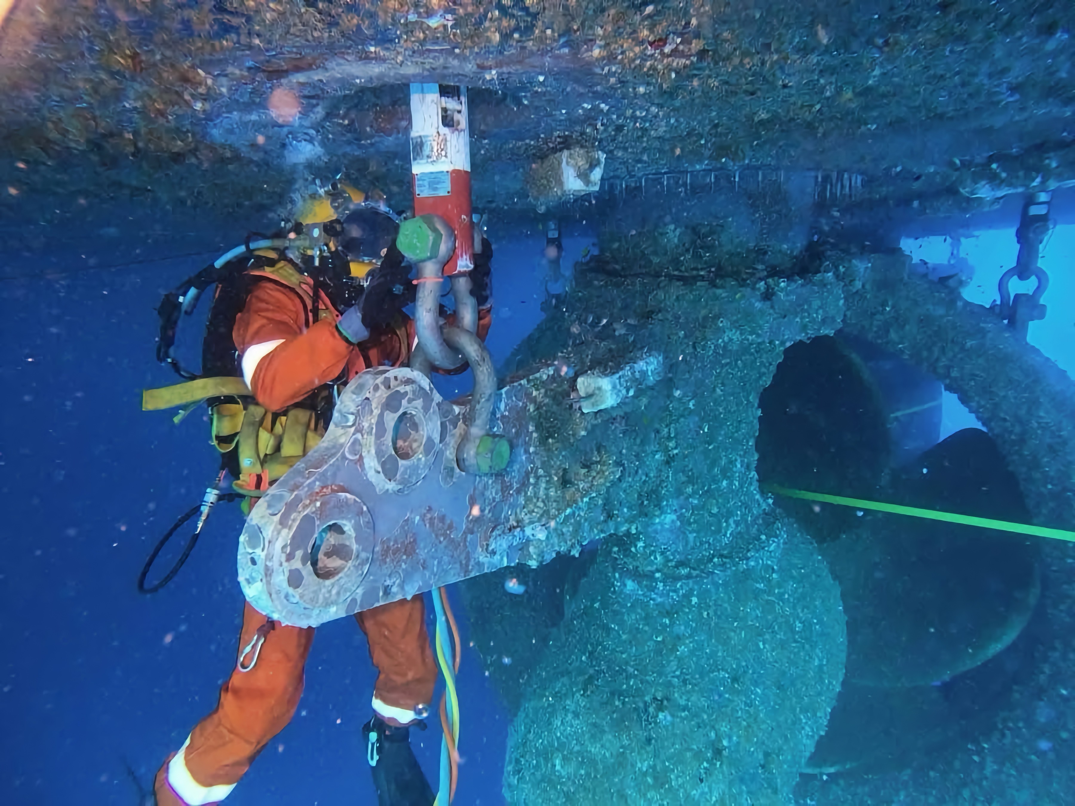 Commercial diver performing in-water propeller inspection and biofouling removal on a bulk carrier, highlighting hydrodynamic roughness and propulsion efficiency impact.