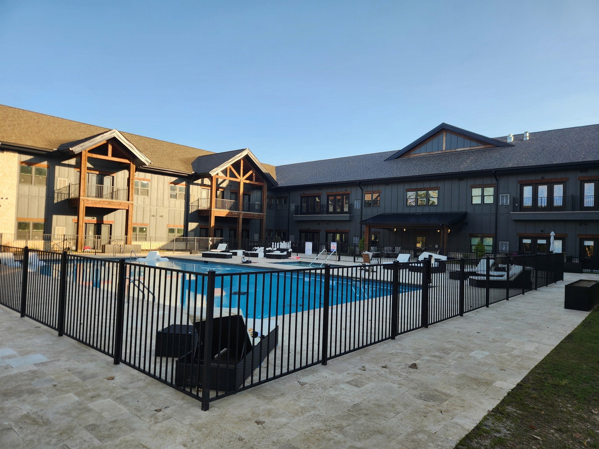 Modern indoor space with large glass doors, lush greenery, and a cozy seating area visible beyond.