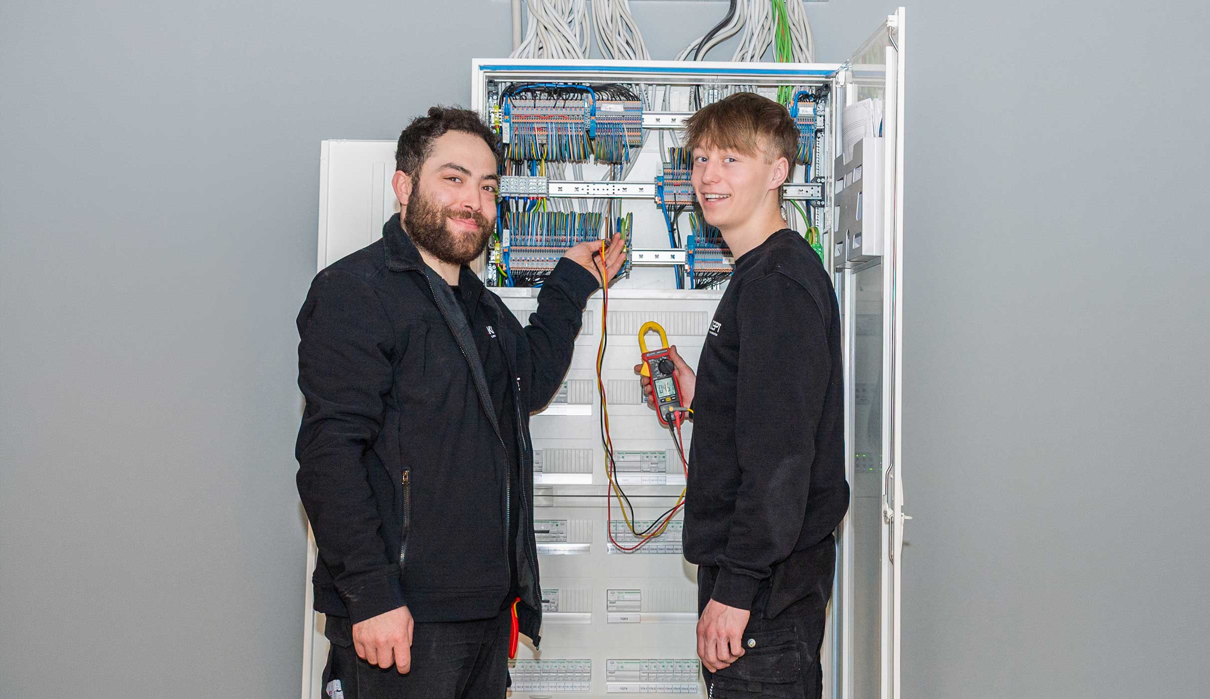 Elektriker bei der Arbeit, zwei Männer an Schaltschrank