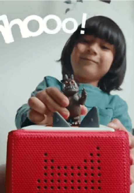 Kid with dark hair and bangs playing with a toy on a red box