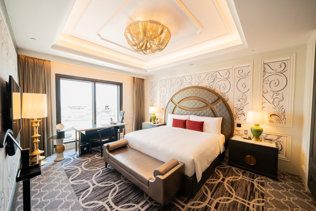 Luxurious hotel bedroom featuring a large bed with decorative headboard, elegant desk area, and stylish lighting.