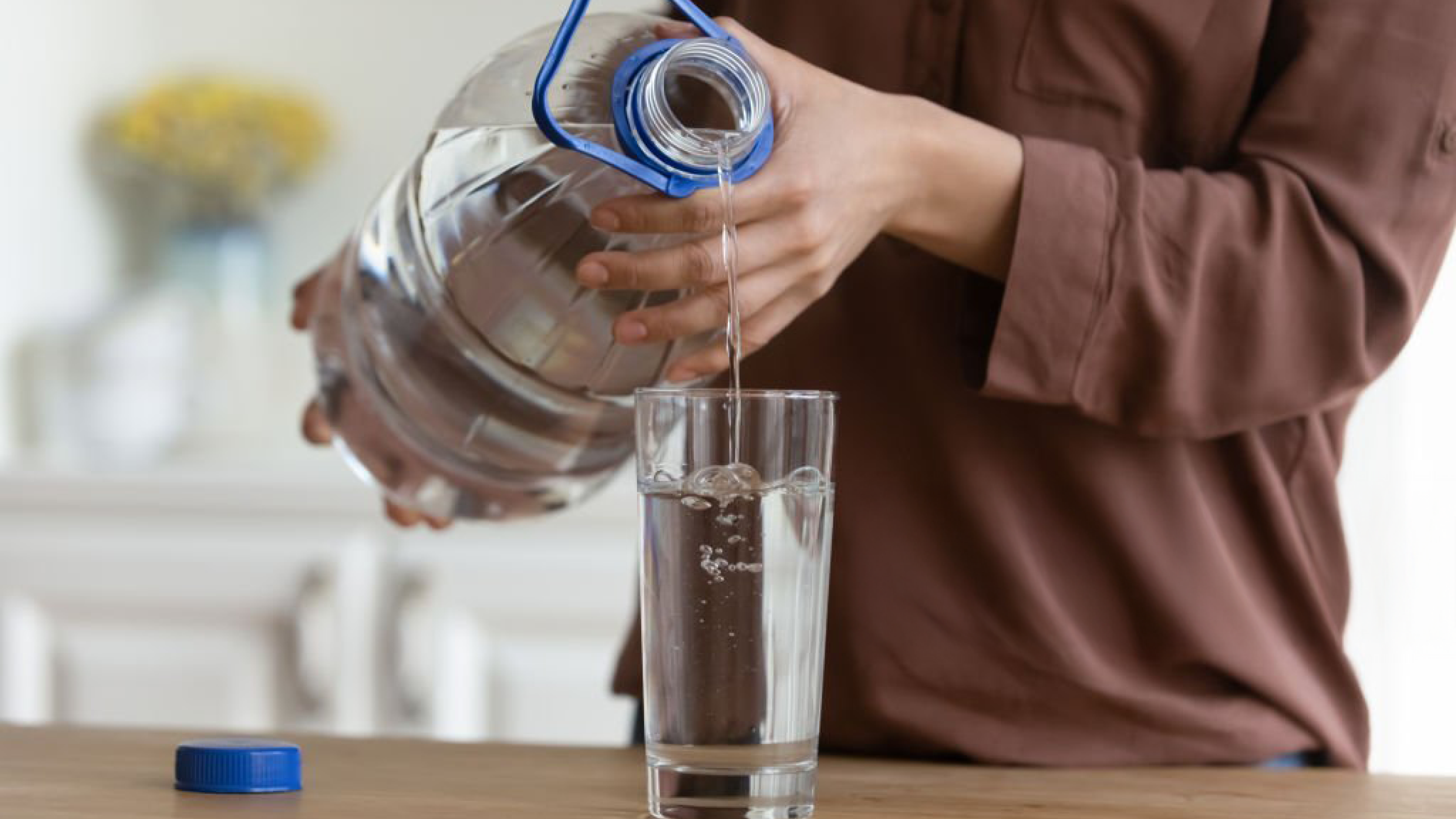 Close-up of hands pouring water from a large bottle into a glass, illustrating the vital role of hydration in maintaining healthy, supple skin during the winter months. Nivea Soft Light Moisturizer Cetaphil Moisturizing Cream Pond’s Cold Cream Plum E-Luminence Deep Moisturizing Crème Himalaya Nourishing Skin Cream Vaseline Intensive Care Cocoa Glow Dove DermaSpa Winter Care Lotion Mamaearth CoCo Body Lotion L’Oréal Paris Revitalift Hyaluronic Acid Serum The Ordinary Hyaluronic Acid 2% + B5 Eucerin Advanced Repair Cream Kiehl’s Ultra Facial Cream Nivea Cocoa Butter Body Lotion Vaseline Aloe Soothe Lotion L'Oréal Paris Hydra-Total 5 Daily Moisturizer Maybelline Baby Lips Biotique Bio Fruit Whitening Lip Balm Lotus Herbals Safe Sun 3-in-1 Matte Sunscreen Neutrogena UltraSheer Dry-Touch Sunscreen Nivea Hand Cream Glycerin & Beeswax The Body Shop Almond Milk Hand Cream Dove Deep Moisture Body Wash Cetaphil Gentle Skin Cleanser Vaseline Healthy White Lightening Lotion L'Oréal Paris Revitalift Brightening Moisturizer Dove Deep Care Body Lotion Burt's Bees Beeswax Lip Balm Vaseline Lip Therapy Innisfree Green Tea Seed Serum Laneige Water Sleeping Mask COSRX Advanced Snail 96 Mucin Power Essence Dr. Jart+ Ceramidin Cream Etude House Moistfull Collagen Cream Sulwhasoo First Care Activating Serum Belif The True Cream Aqua Bomb Skinfood Royal Honey Propolis Enrich Essence Missha Time Revolution The First Treatment Essence Klairs Rich Moist Soothing Cream Pyunkang Yul Moisture Ampoule MISSHA Super Aqua Ultra Hyalron Emulsion Dove Deeply Nourishing Body Wash DOVE Body Love Supple Bounce Body Lotion for Dry Skin DOVE Beauty Cream Bar Imported DOVE beauty Skin whitening cream DOVE Restoring Ritual Body Lotion DOVE Body Love Light Hydration Body Lotion Dove DermaSeries Dry Skin Relief Body Lotion