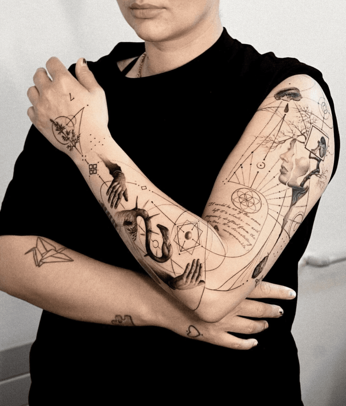 Full-arm tattoo combining hands, snakes, and geometric symbols.