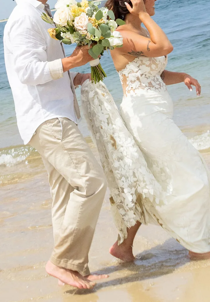 Bride and groom walking barefoot through the surf with her bouquet, by Sioux Falls, SD wedding photographer Kelsey Lynn