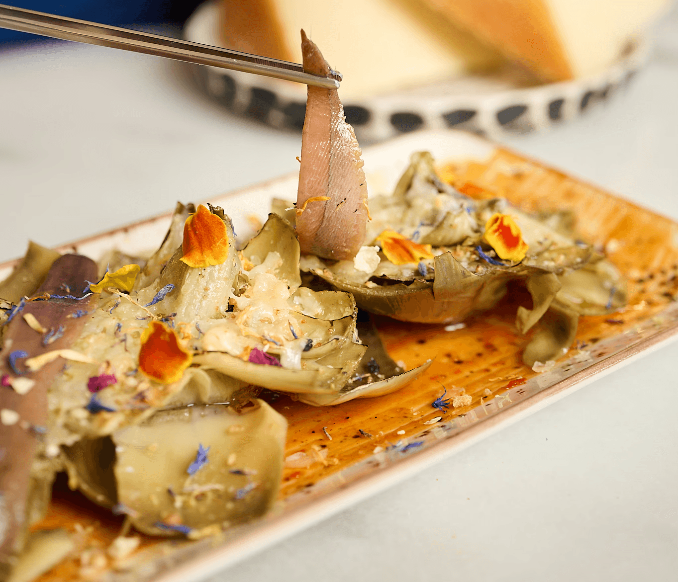 Corazones de alcachofa confitados con mojo picón, anchoas Casa Santoña, queso viejo tostado y ralladura de limón, entrante de Hatillo.