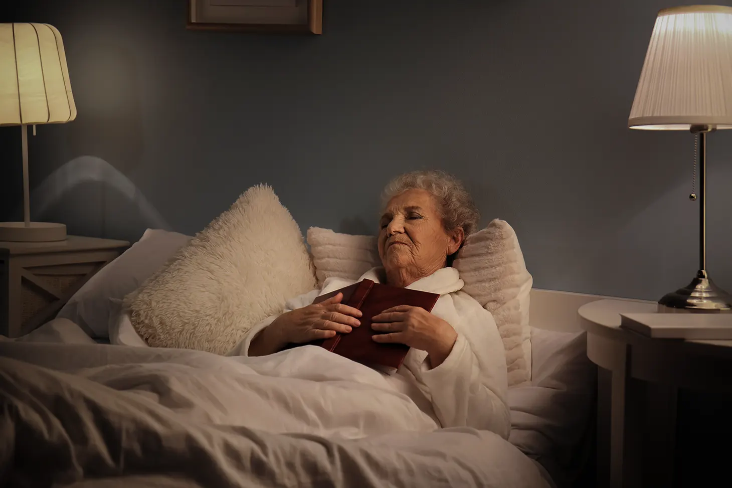 Kvinne som hviler i sengen med bibelen liggende over brystet.