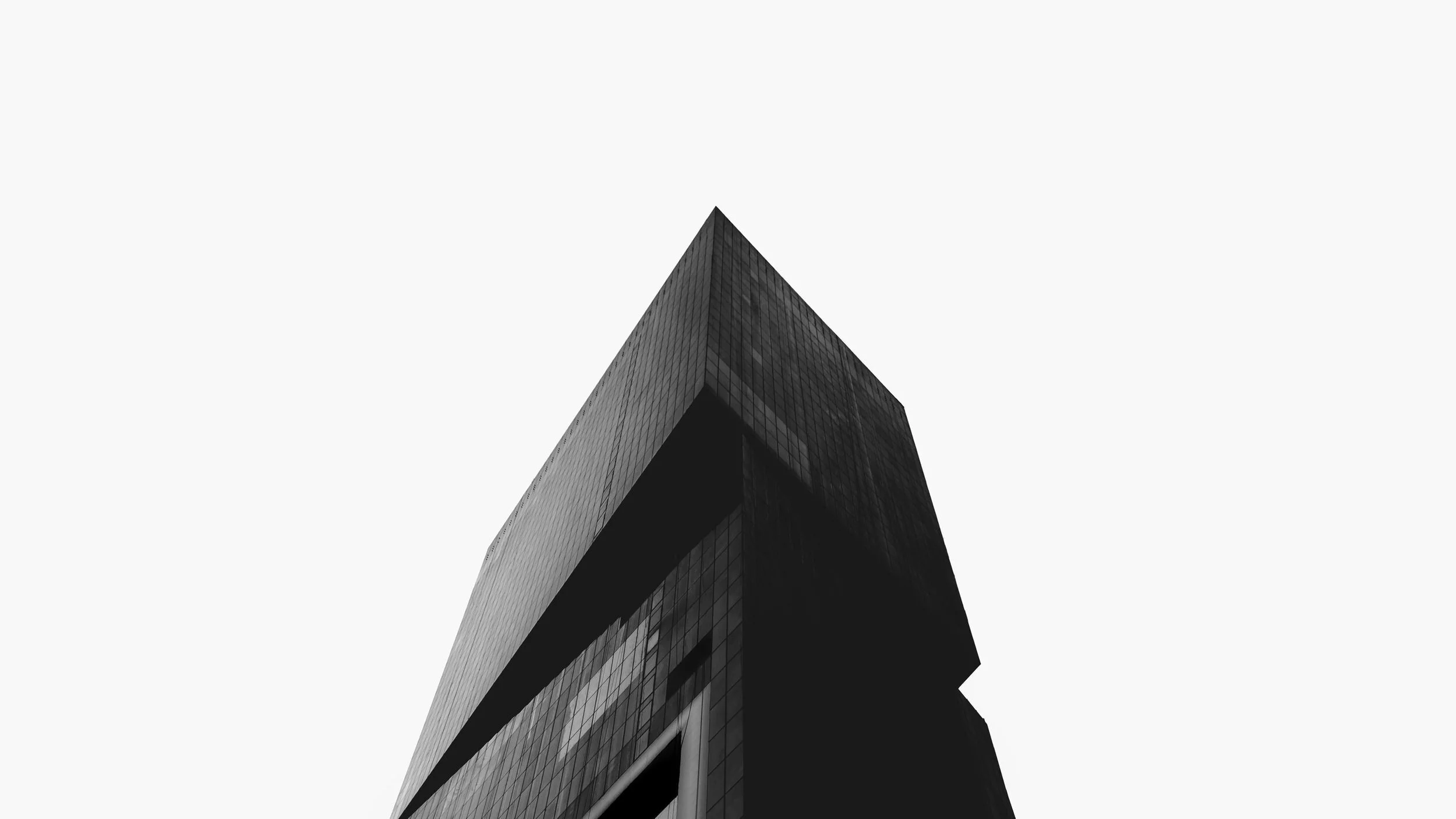 An abstract black building with a sharp pointed top, set against a simple white background.