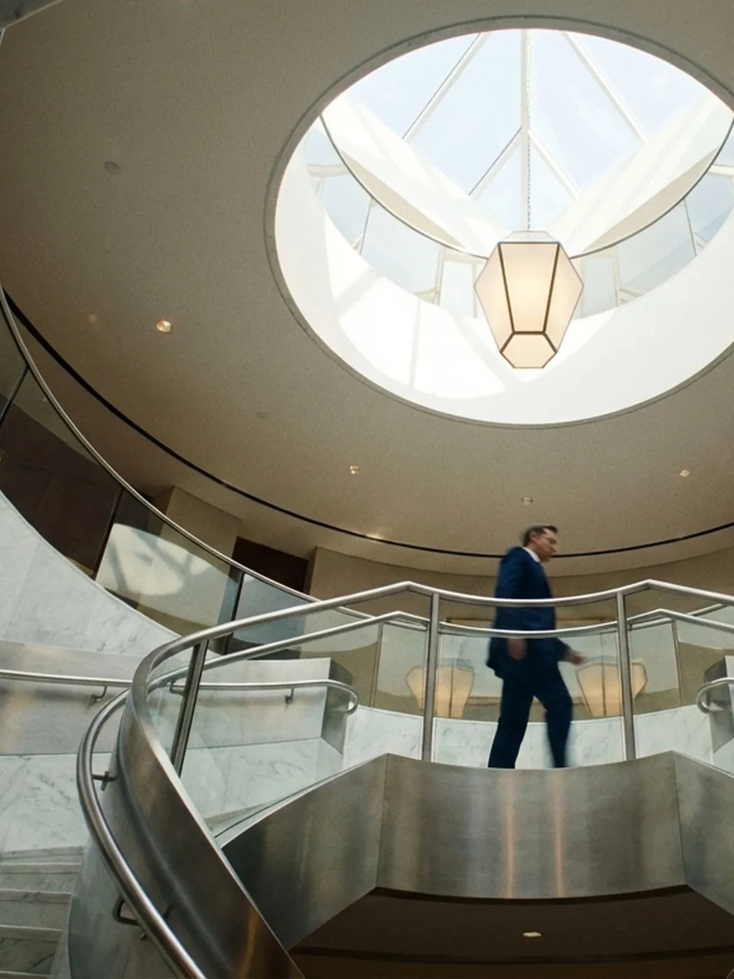 Man in suit walks down spiral staircase.