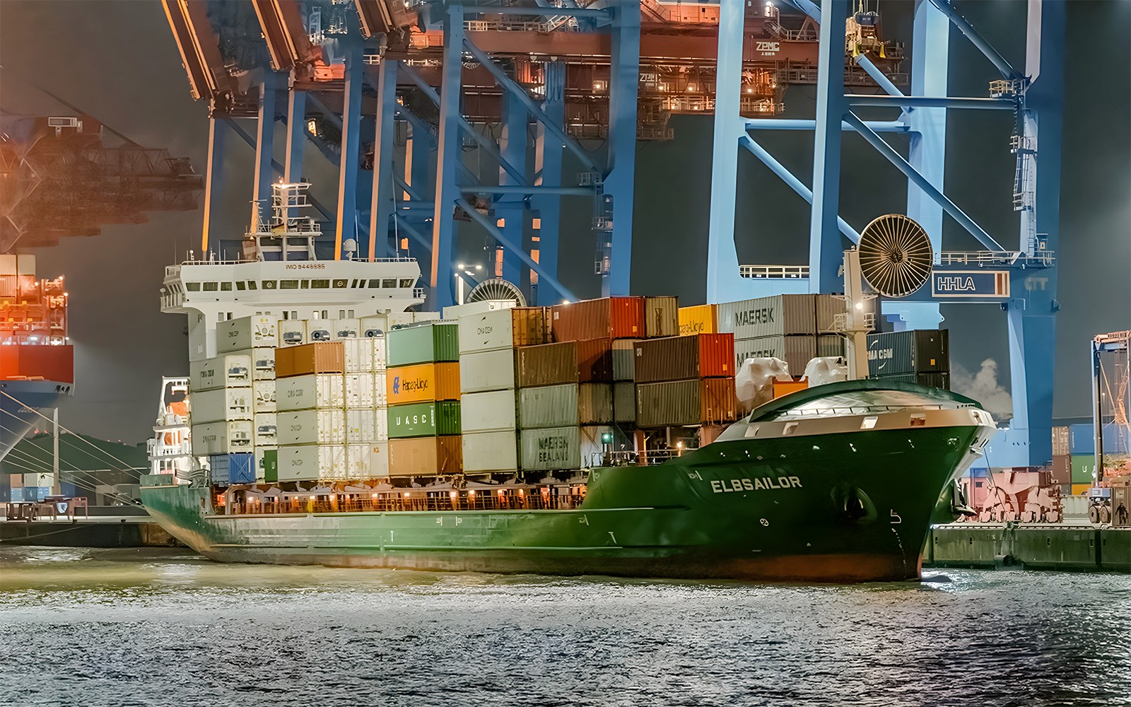 货船在夜间停靠在大港，伴随着晚间灯光巡游。