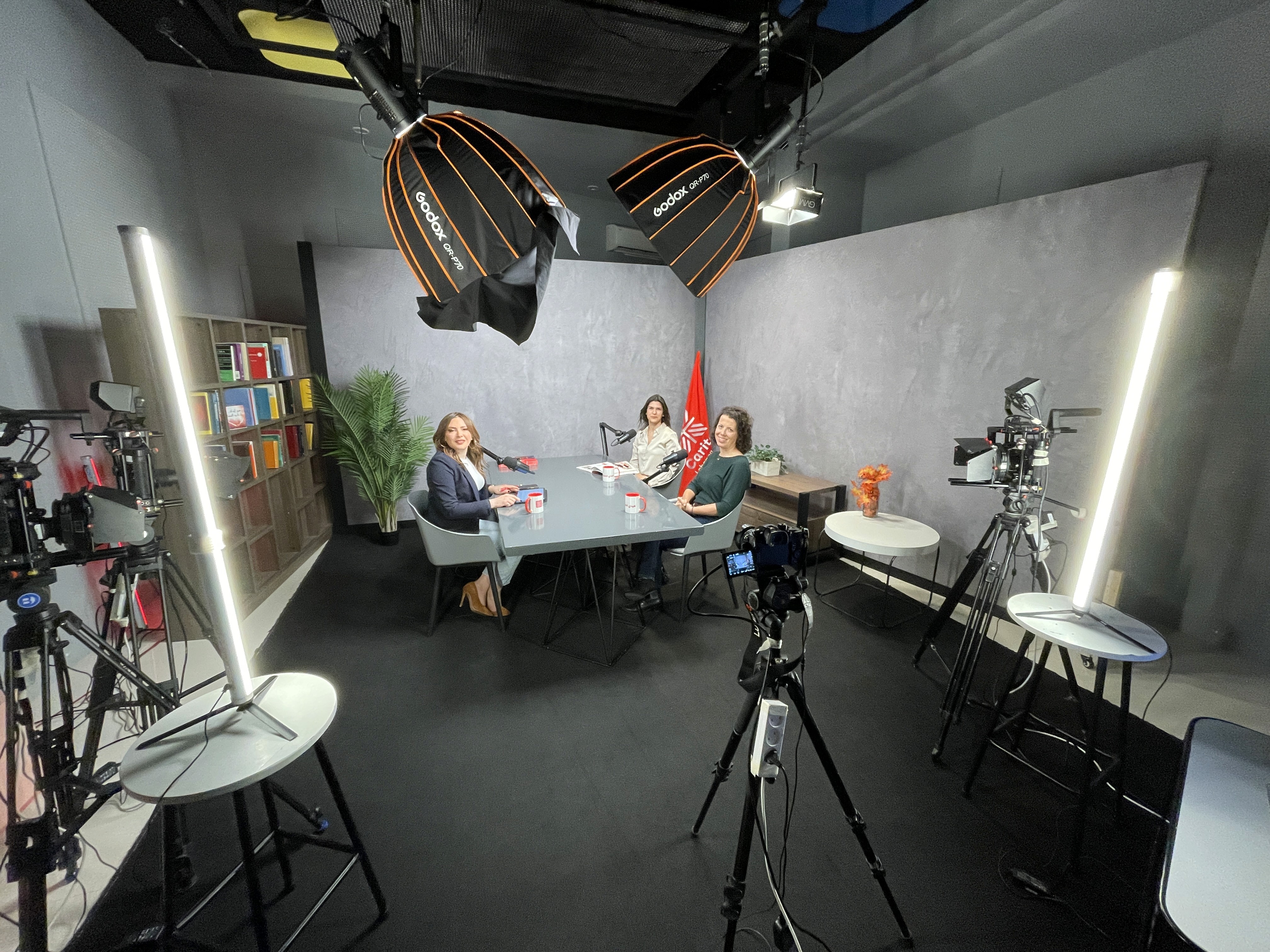 Black and white image of people working at a table with laptops, showing hands gesturing during discussion of digital content displayed on screens, with fabrica® logo in the corner.