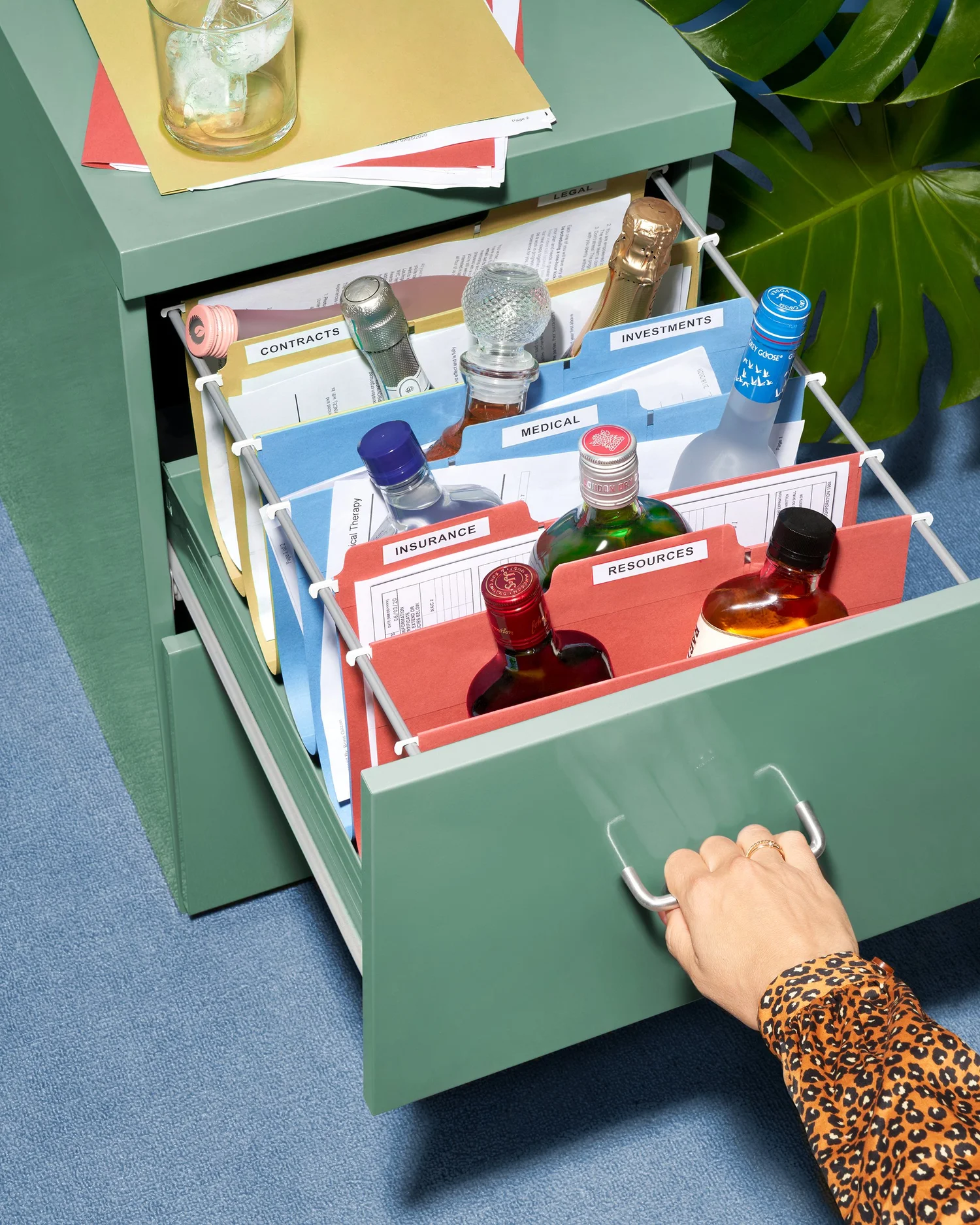 An open green filing cabinet drawer filled with various bottles placed inside each folder. Showcasing the fun side of design with resources.