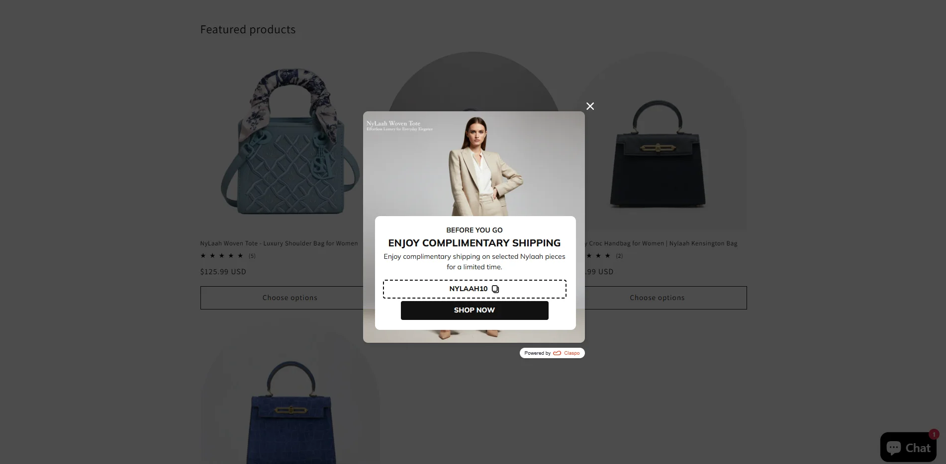 A centered exit-intent cart abandonment popup by Claspo on a luxury e-commerce fashion website intercepting leaving users with a complimentary shipping offer and a copyable promo code box.