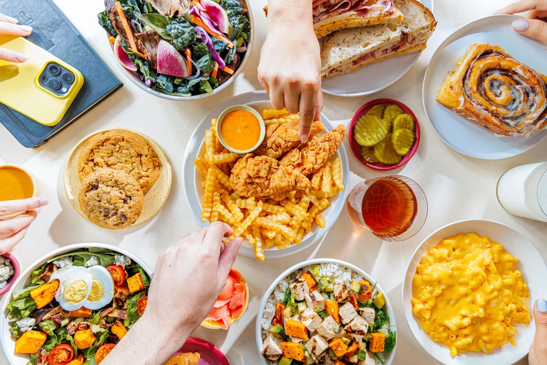 Top view of people's hands while sharing a large meal.