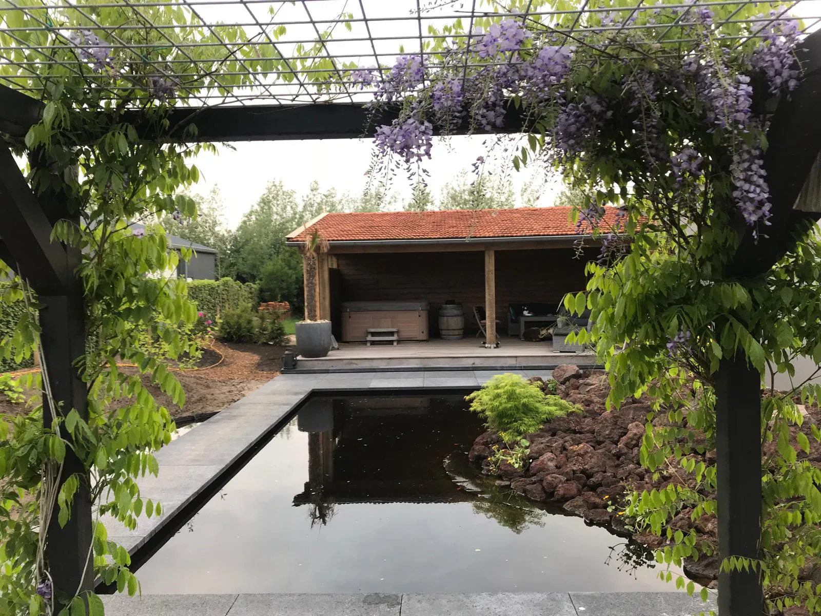 Houten overkapping met zithoek aan vijver in tuin bij woning in Gorredijk en omliggende dorpen