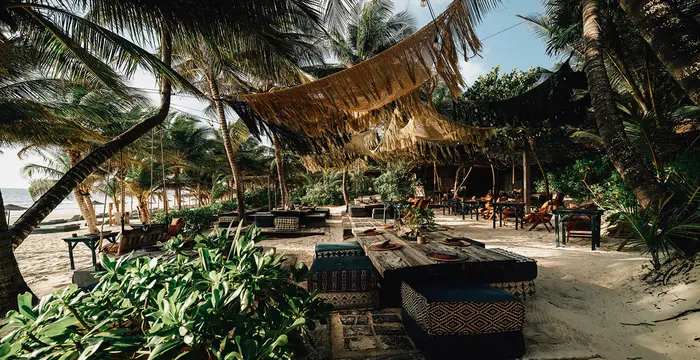 Relaxed and jungle-like restaurant called La Popular, located in front of the sea and surrounded by nature, palm trees, and a selvatic look at Nômade Tulum, Mexico.