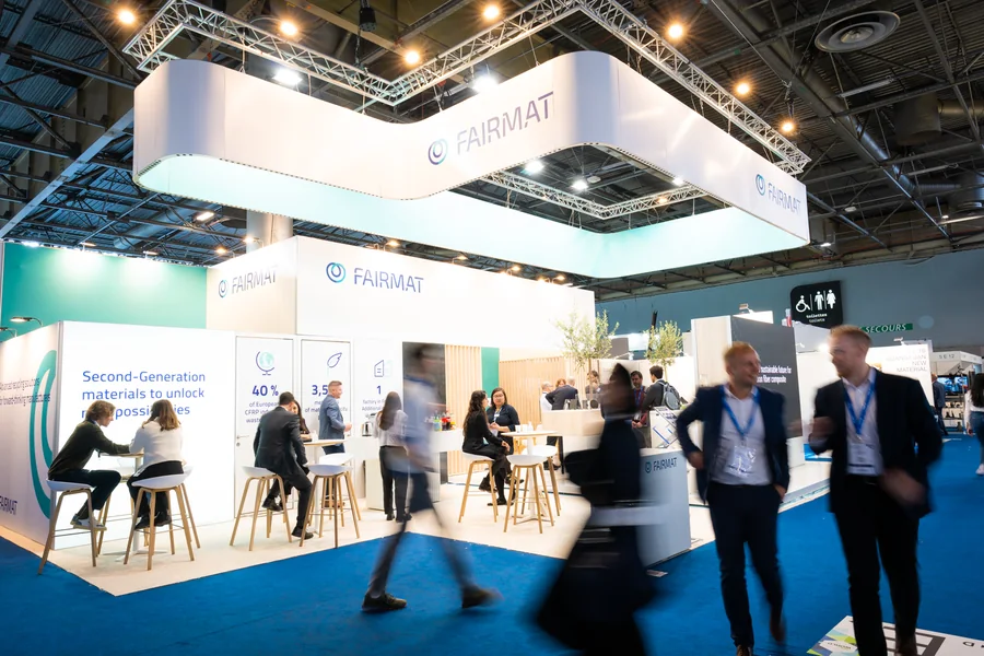Stand Fairmat sur un salon professionnel, avec des visiteurs en mouvement et des échanges sur le stand.