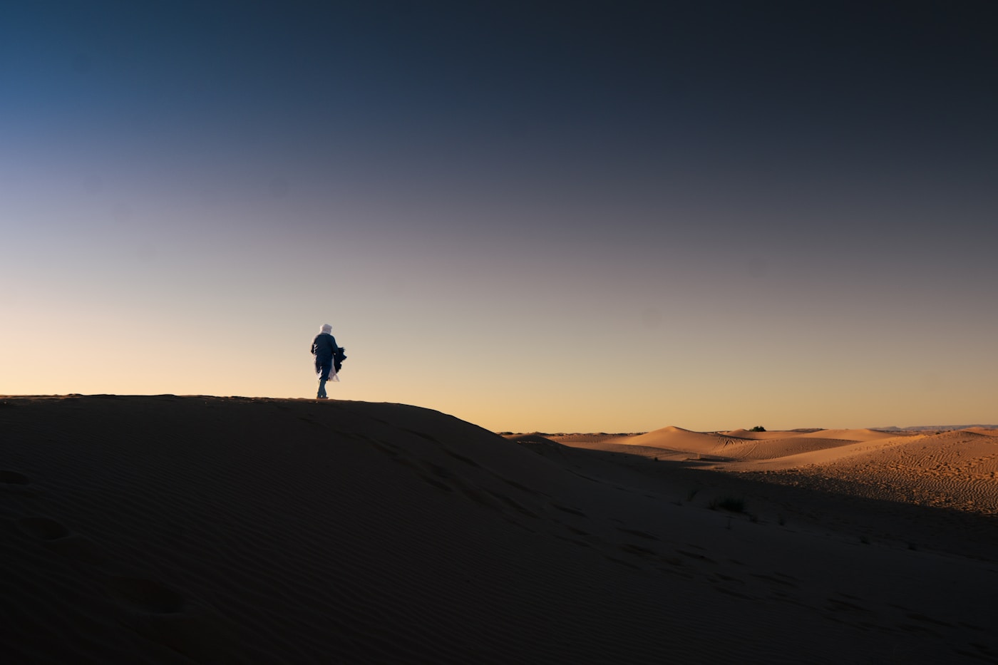 A traveller on a Sossusvlei dune at sunrise, long shadows across the sand