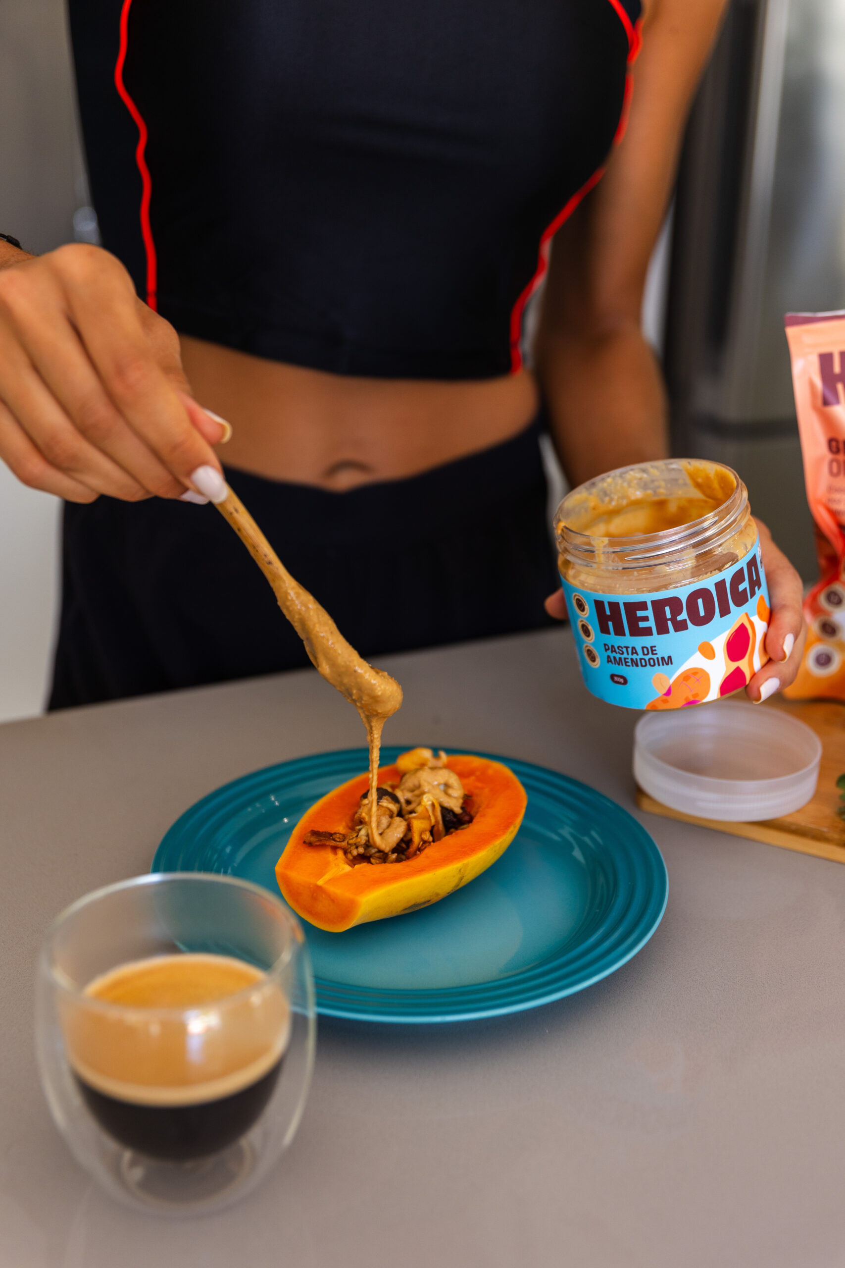 Embalagem de pasta de amendoim, sendo servida em uma mamão com granola.