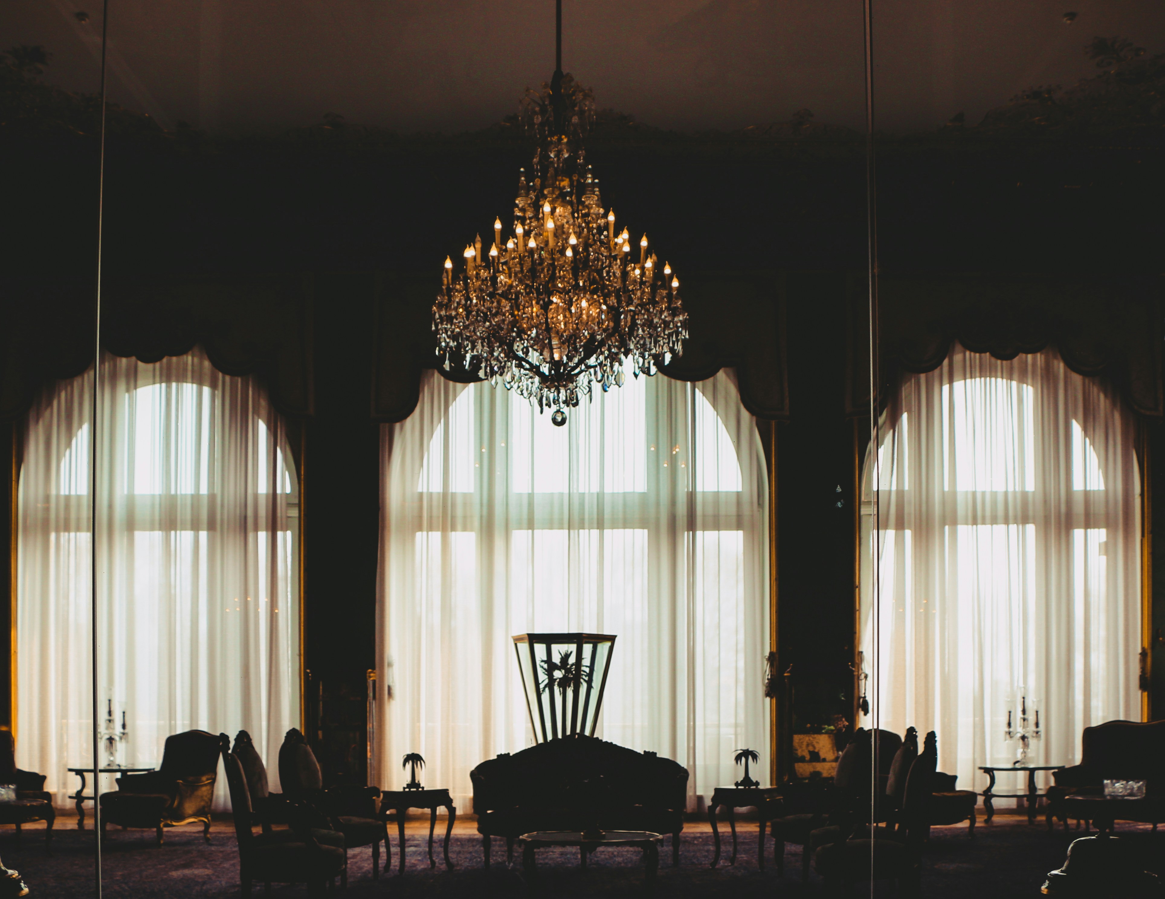 A traditionally designed room with natural light from a window and a chandelier.
