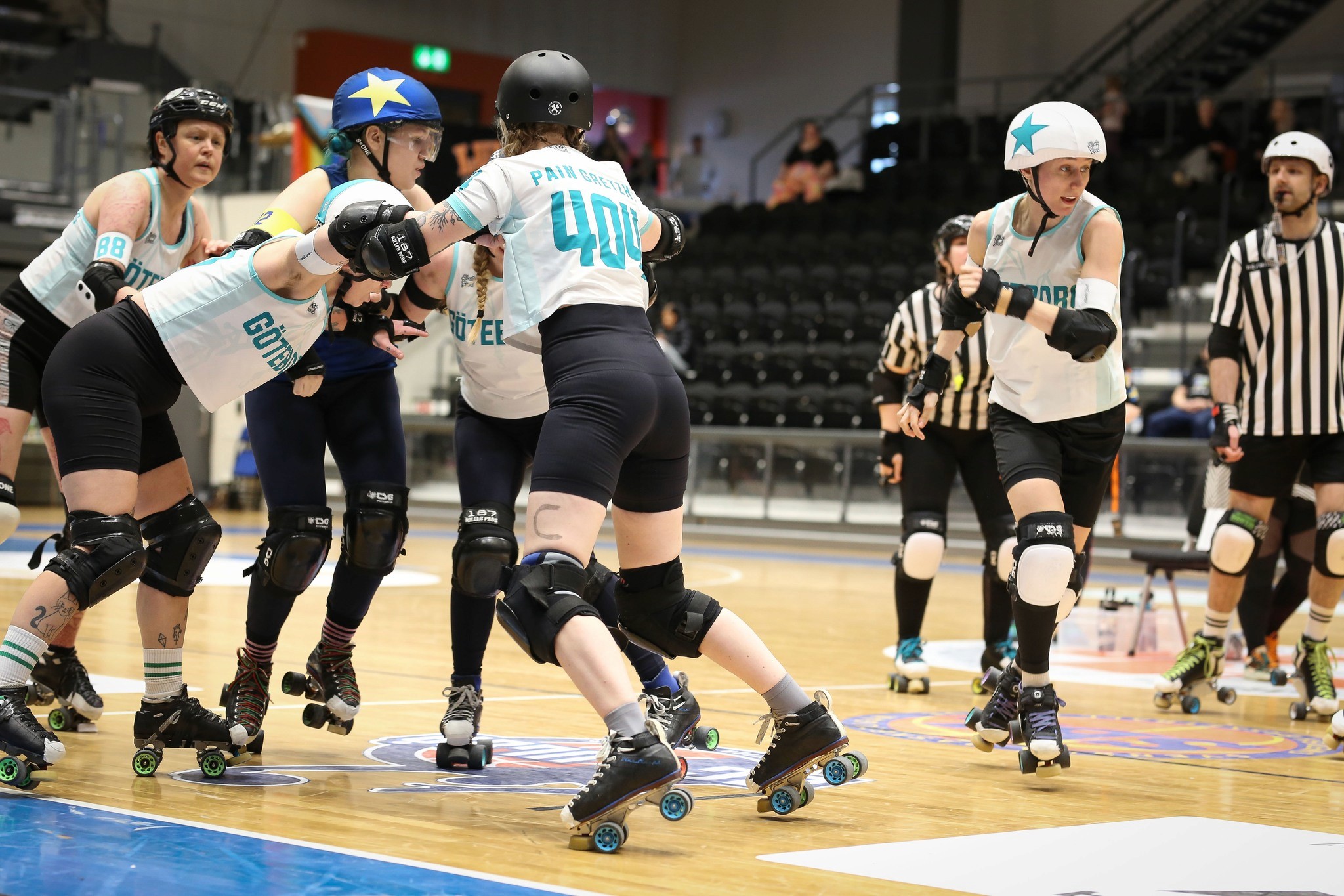 A group of roller derby players sitting on chairs discussing something.