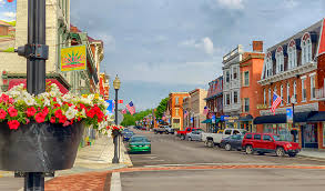 Aerial view of an intersecting dirt pathway forming an X-shape surrounded by lush greenery and arid, rocky terrain, illustrating a contrasting landscape.