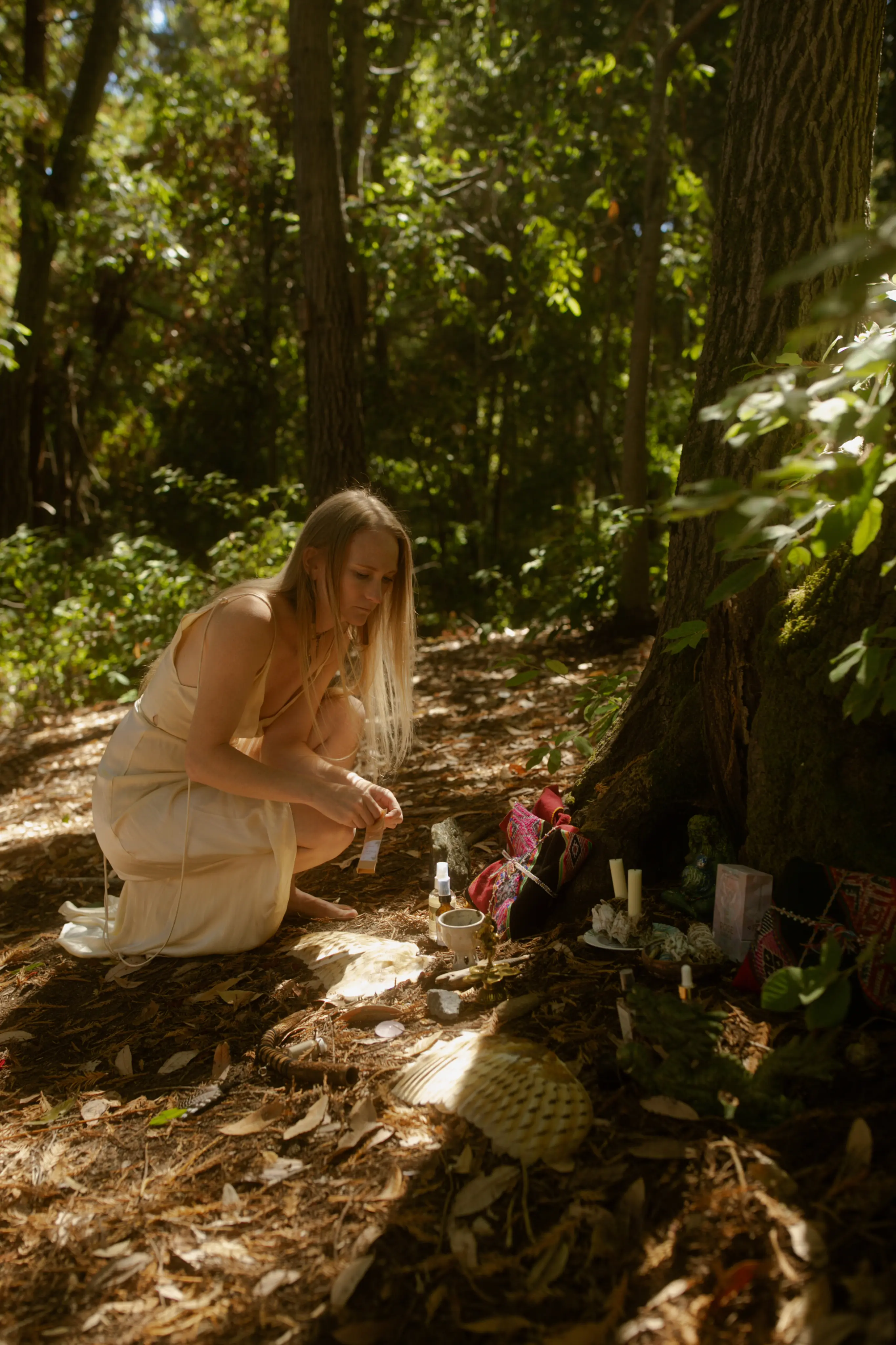Emeline tending a sacred altar with flowers and offerings in the forest