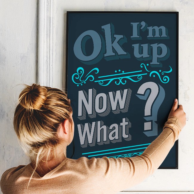 A woman hanging the 'ok I'm up' wall art