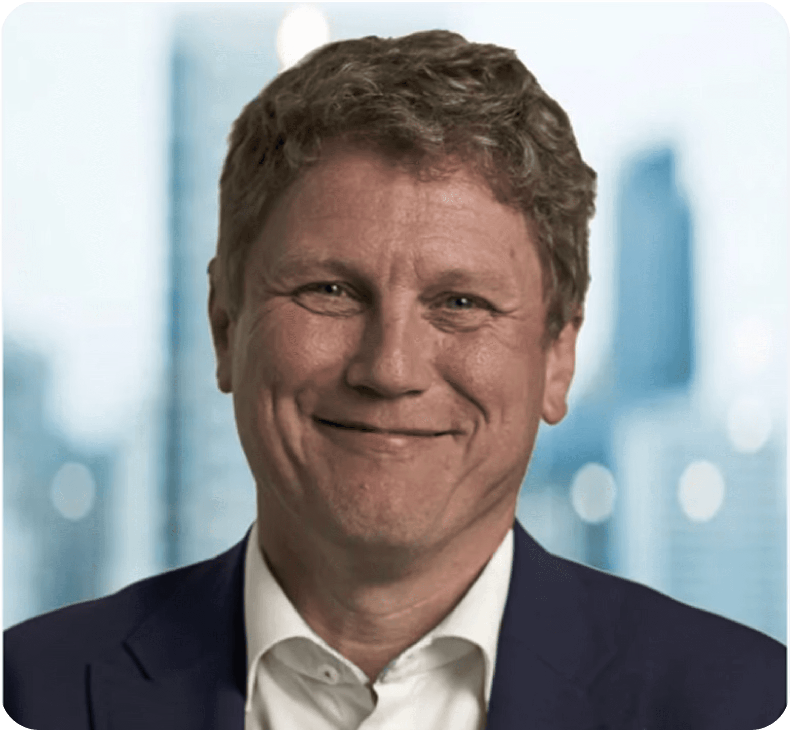 Black and white portrait of a smiling man with short hair, wearing a suit and tie, against a blurred background.