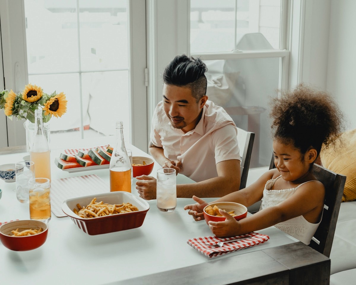 A parent and child sharing a hearty, balanced meal together at the table.