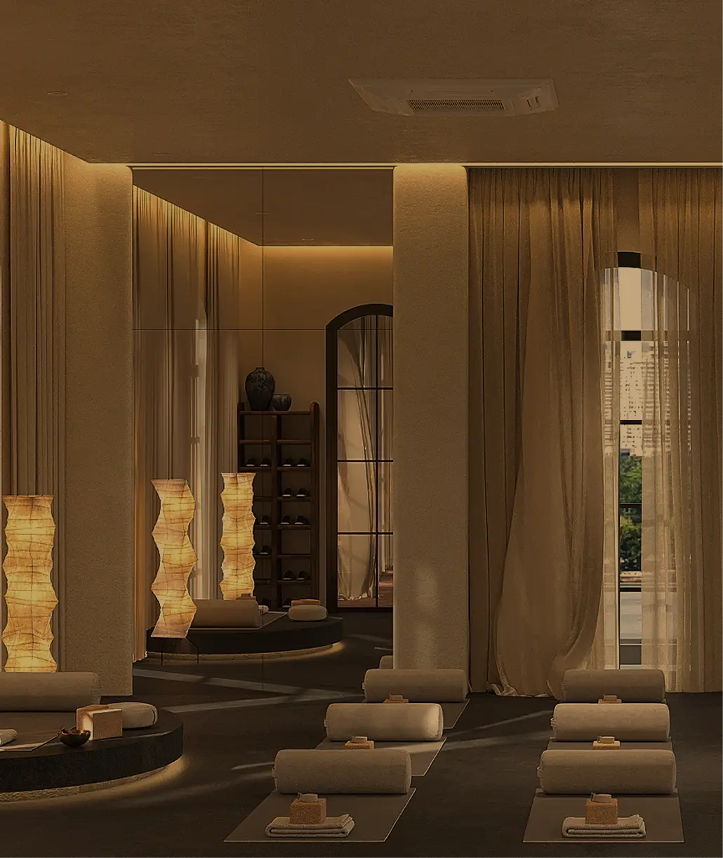 A serene spa room softly illuminated by warm, ambient lighting, featuring cushioned mats for relaxation, tall, textured lamps, and an array of neatly arranged towels and spa essentials against a backdrop of sheer curtains and a wall-length mirror.