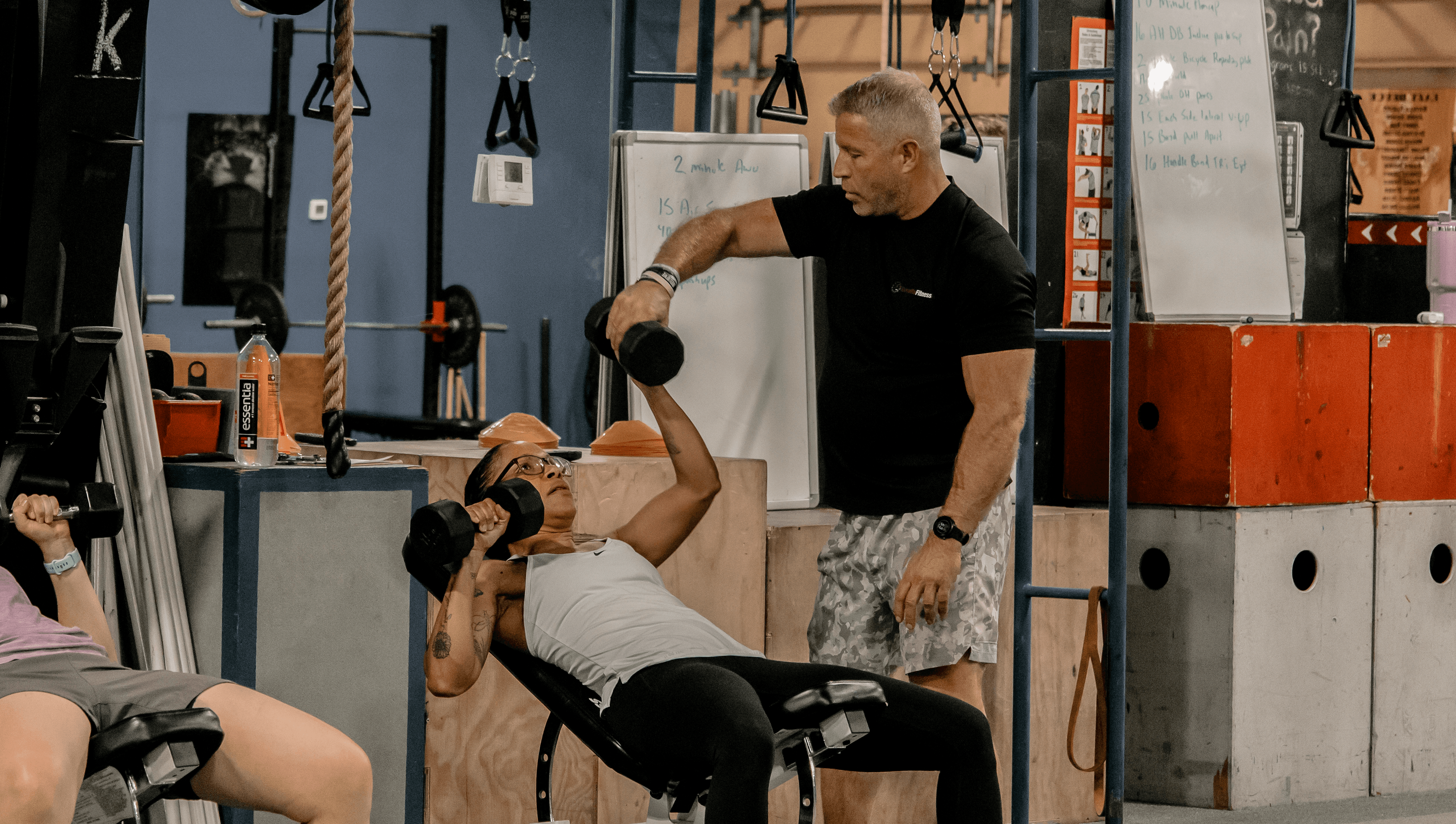 coach helping member with dumbell