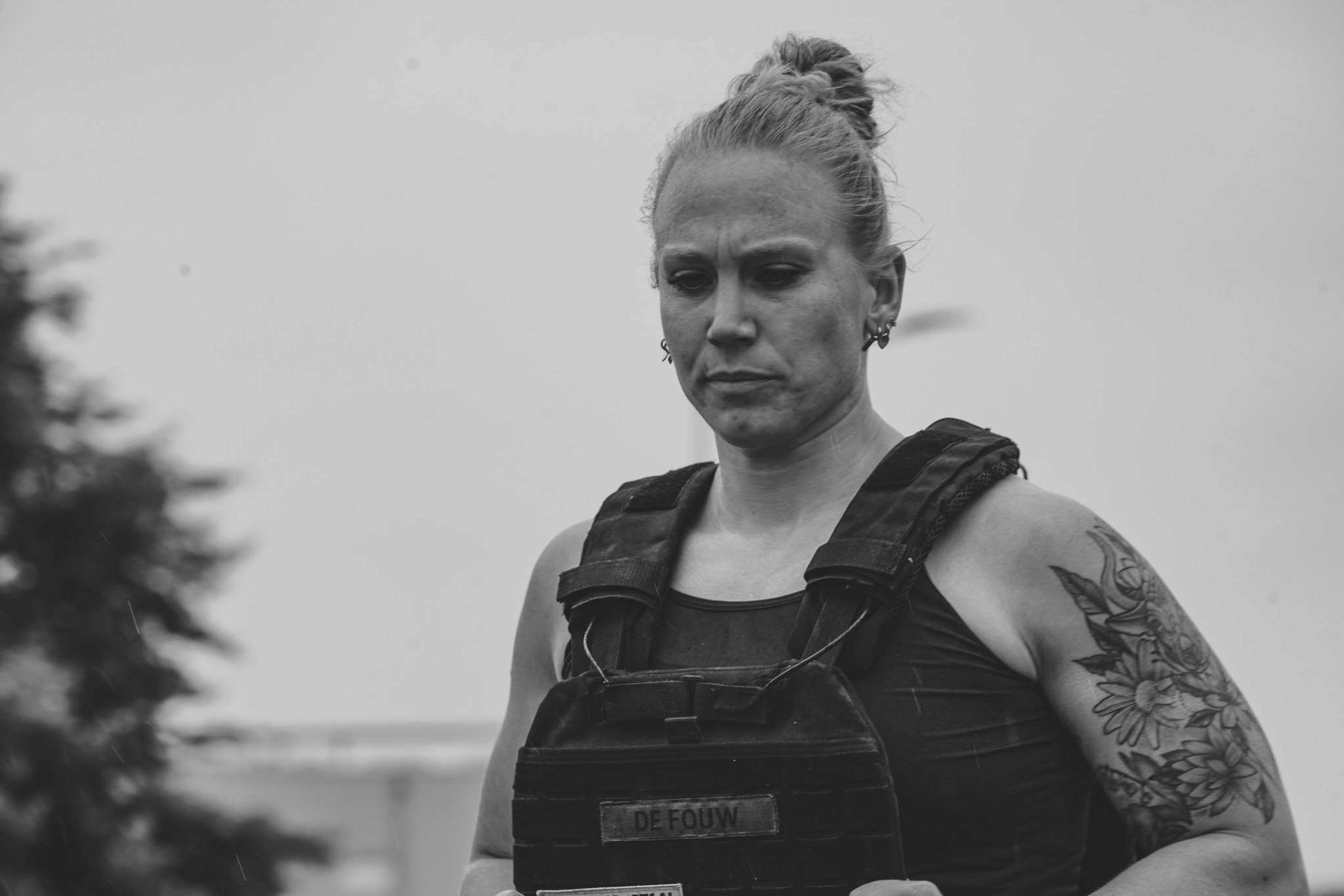 Black and white photo of a woman wearing a weightvest, running.