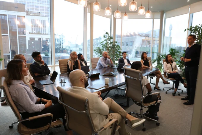Avantia team seated around a modern conference table listening to a presentation in a bright office meeting room.