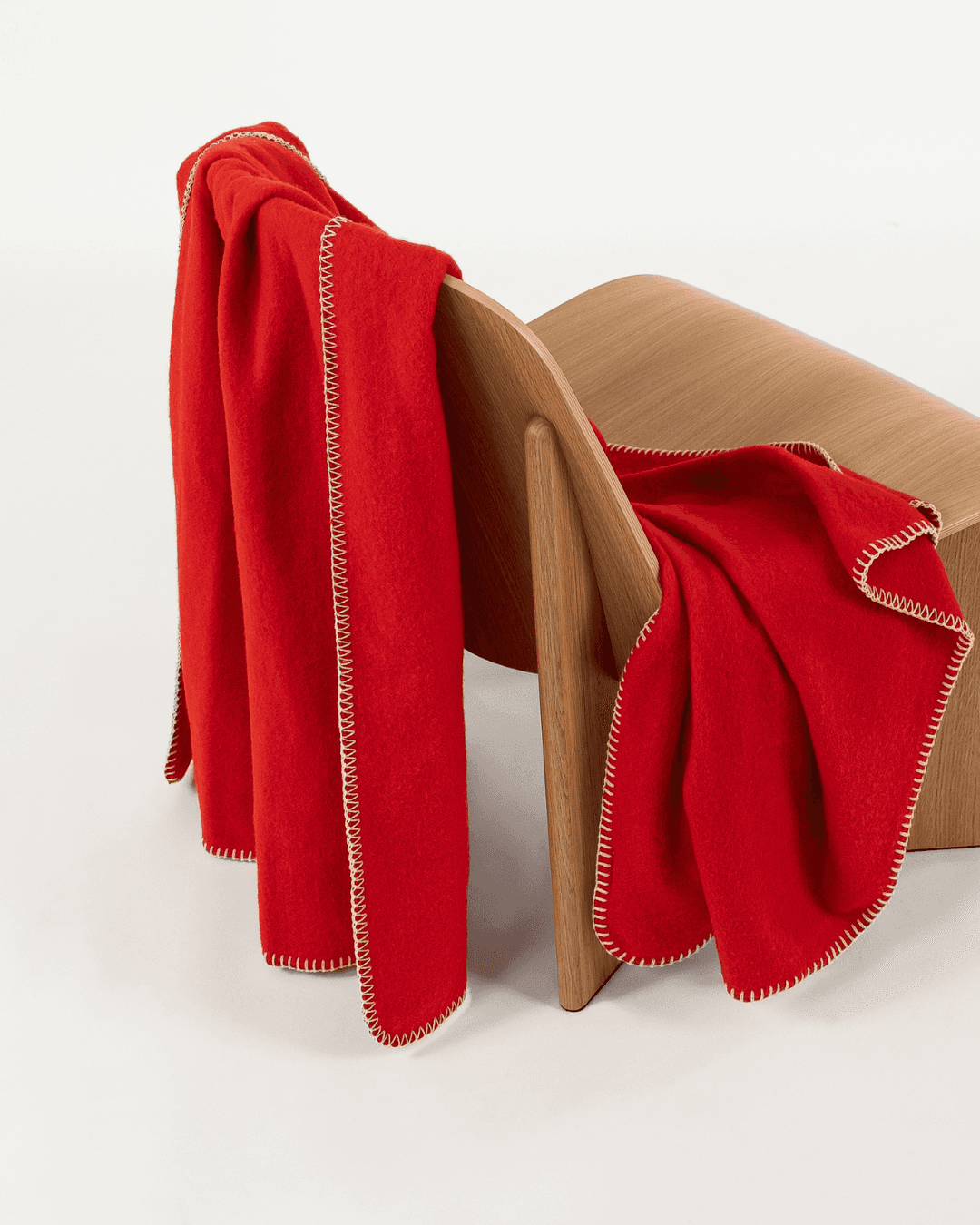 Merino wool blanket in poppy draped over a wooden chair