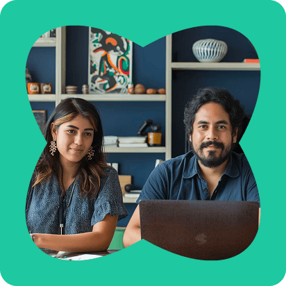 Two people smiling and standing close together against a simple background