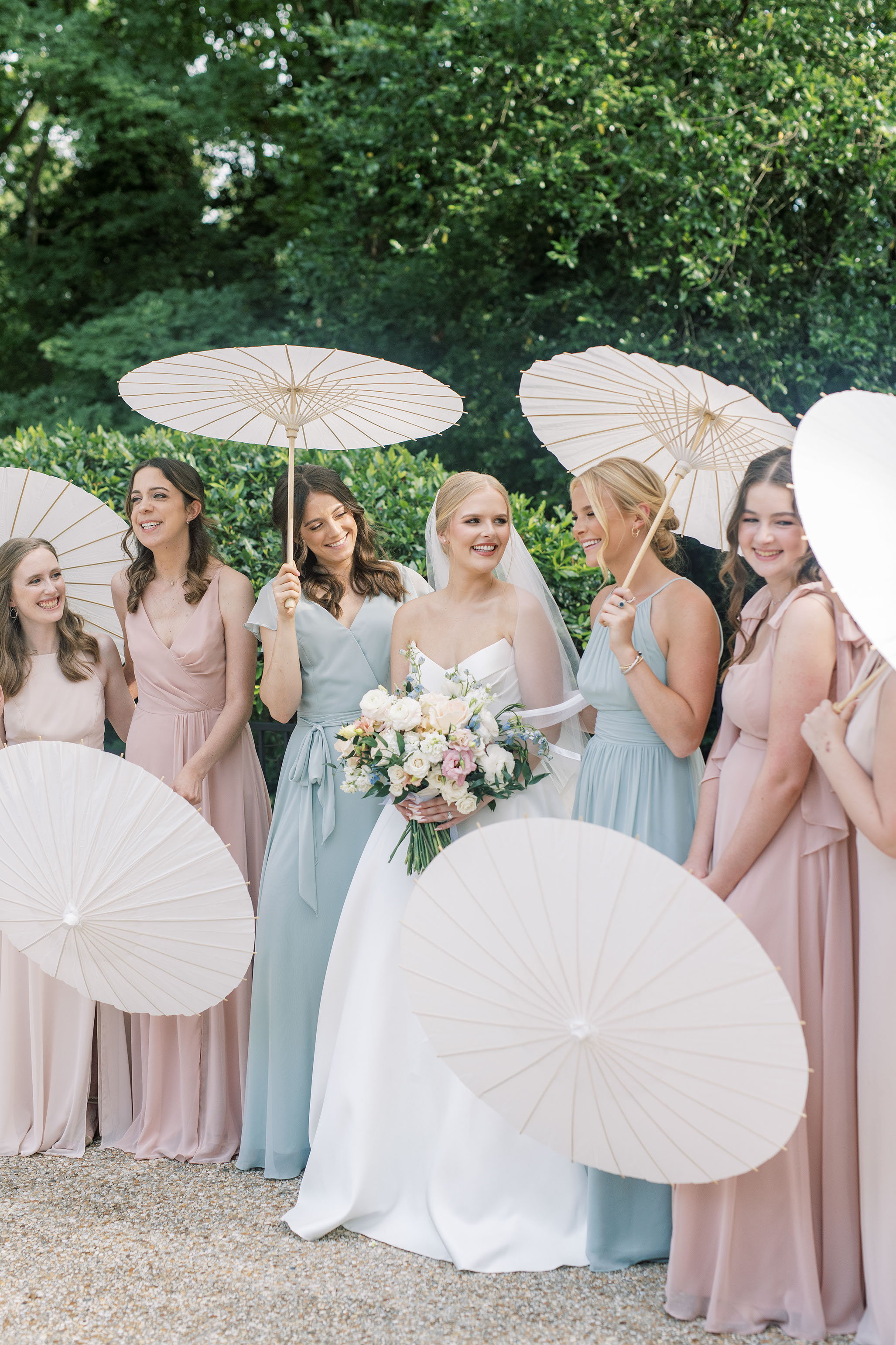 Bride and bridesmaids holding white parasols before the ceremony.