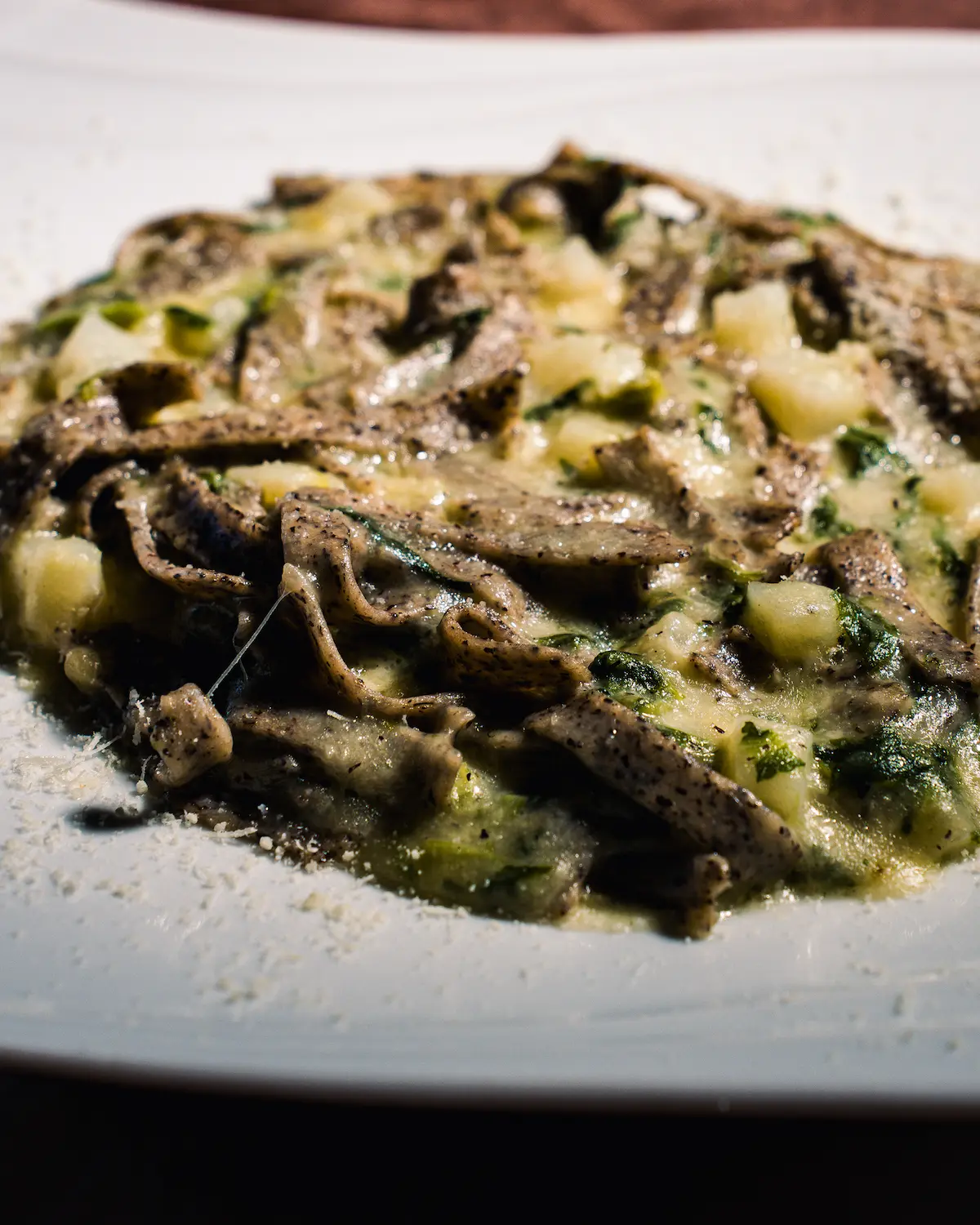 A rustic kitchen scene featuring glass jars of sourdough starter on a wooden table, with a notebook filled with handwritten recipes, a brown bowl of flour, and a beige fabric apron, illuminated by soft natural light from a window.