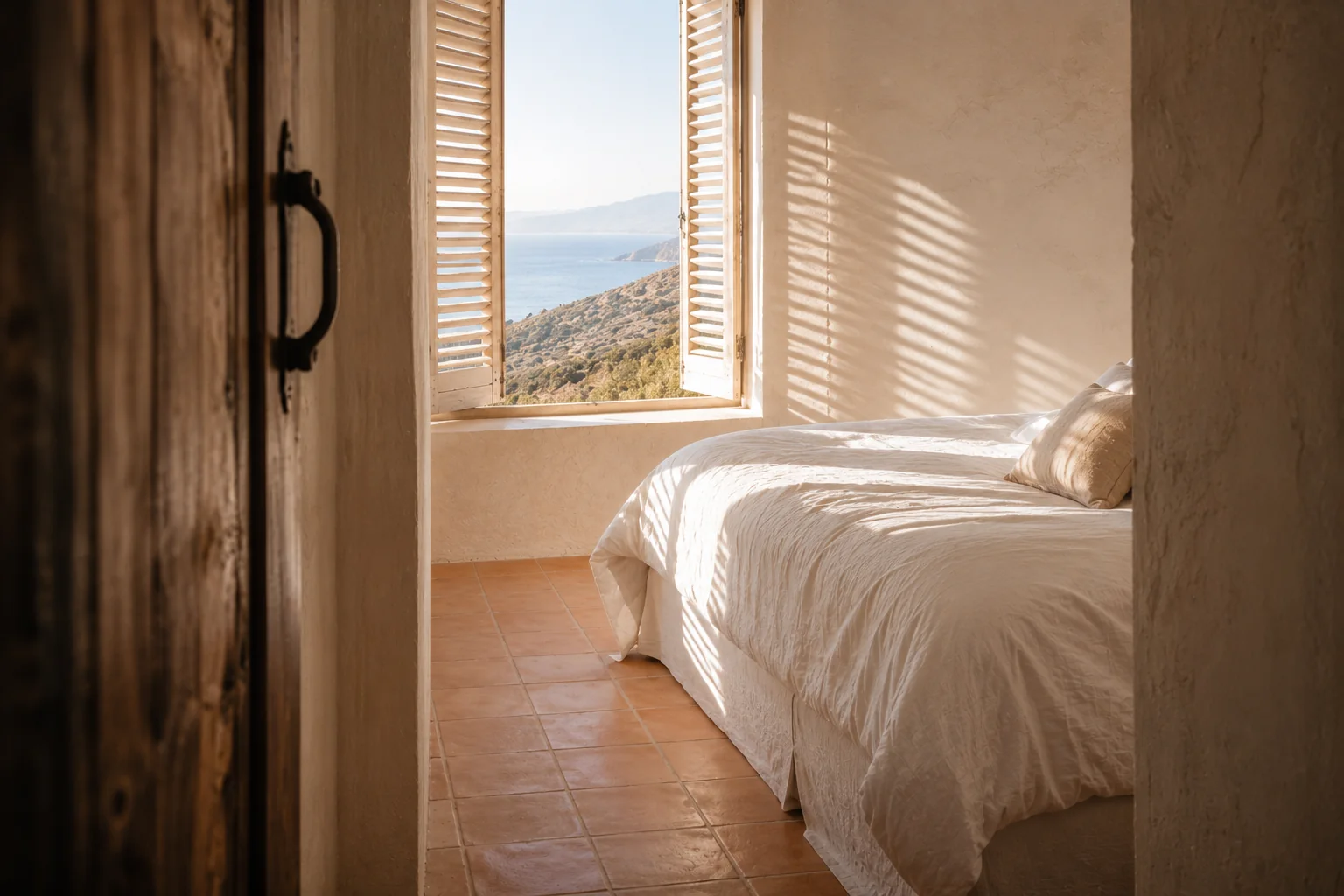 Chambre préparée avec un lit en linge blanc et une fenêtre sur la mer