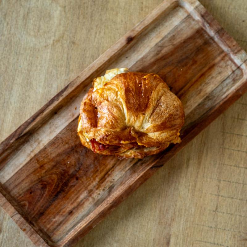 A festive platter of roasted vegetables, including sliced, seared pears or apples and charred tomatoes, garnished with walnuts and rosemary sprigs, set next to a pumpkin, a glass of red wine, and lit candles for a holiday or autumn meal.