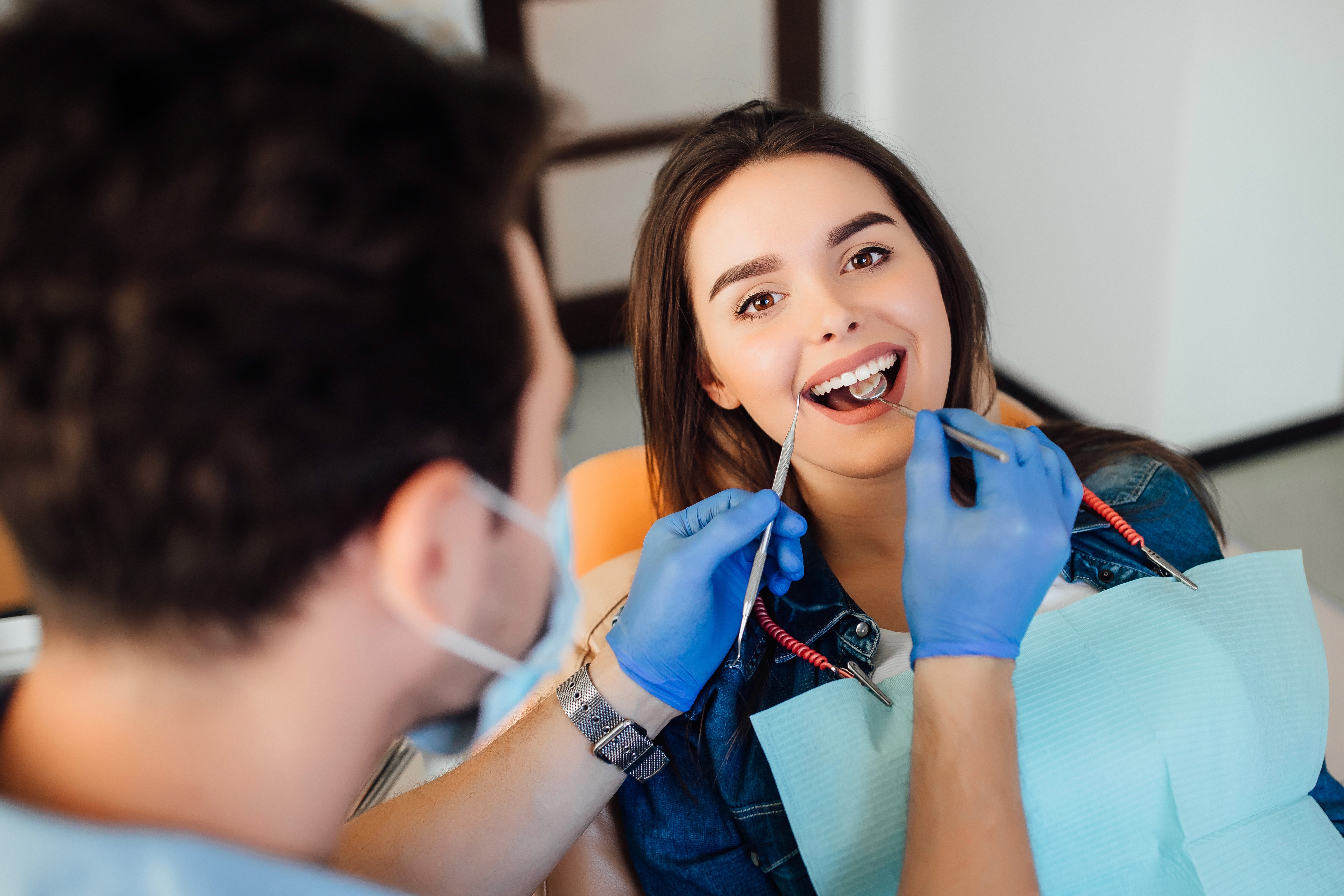 Dentist performing a dental checkup on a smiling patient in a clinic