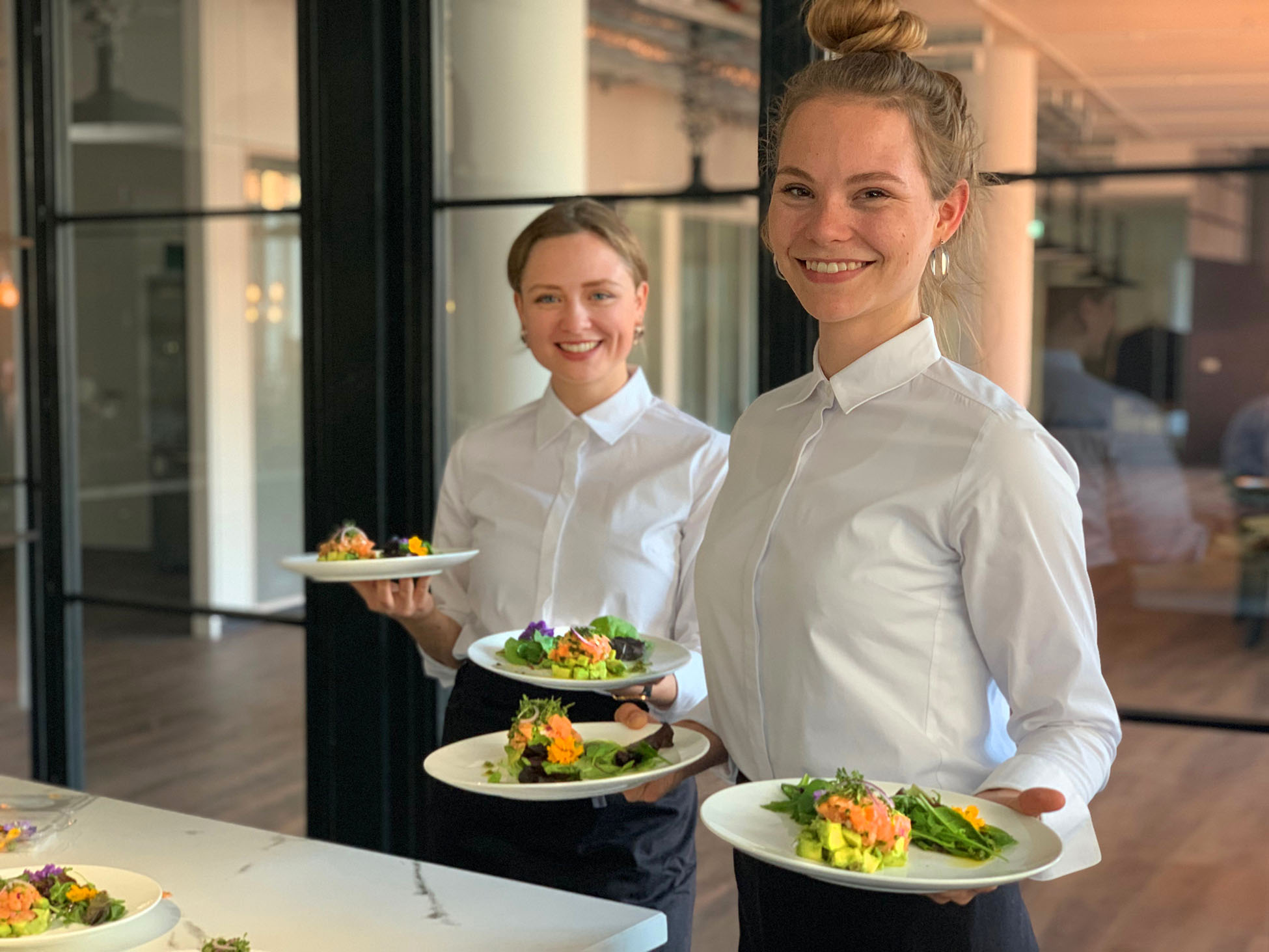 Zwei Servicekräfte tragen angerichtete Teller beim Event Catering
