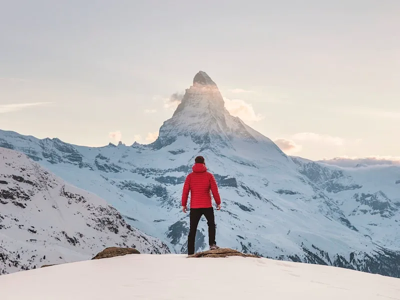 Мъж и жена се целуват на път сред трева и хълмове на заден план