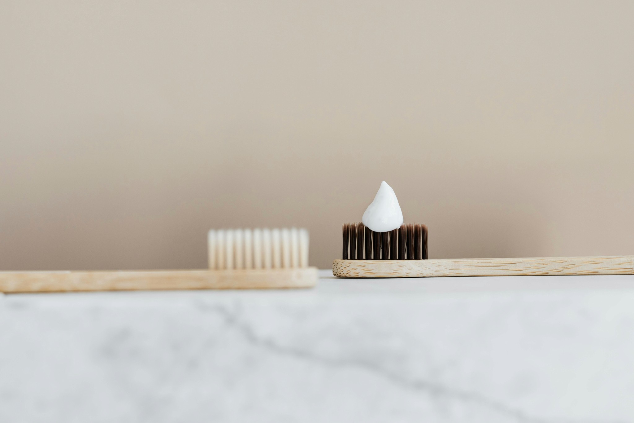 Image of two toothbrushes, one has toothpaste on the bristles