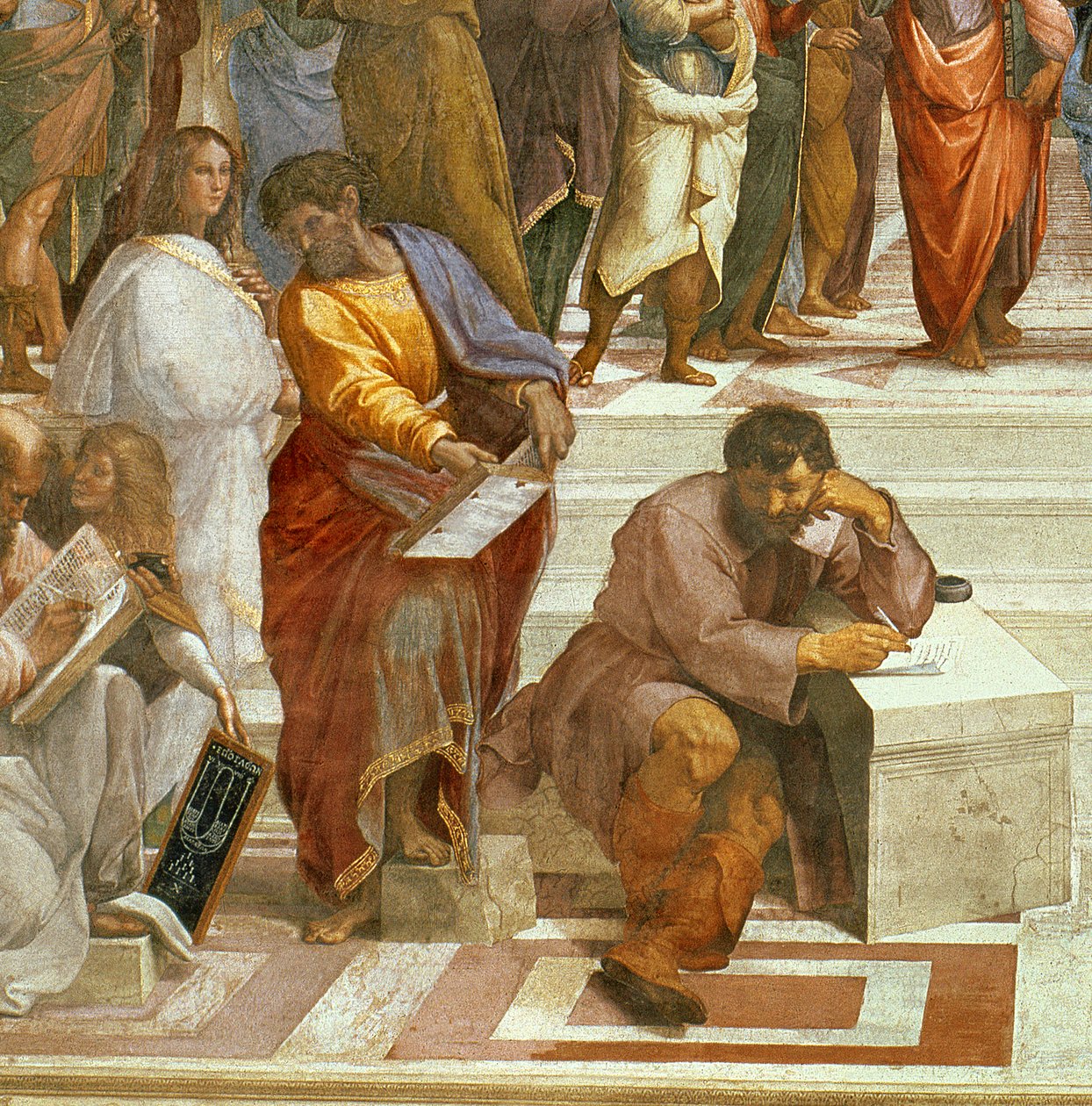 Man with a beard in a dark button-up shirt, smiling while writing in a notebook.