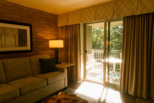 Living room with couch, lamp, and balcony view.
