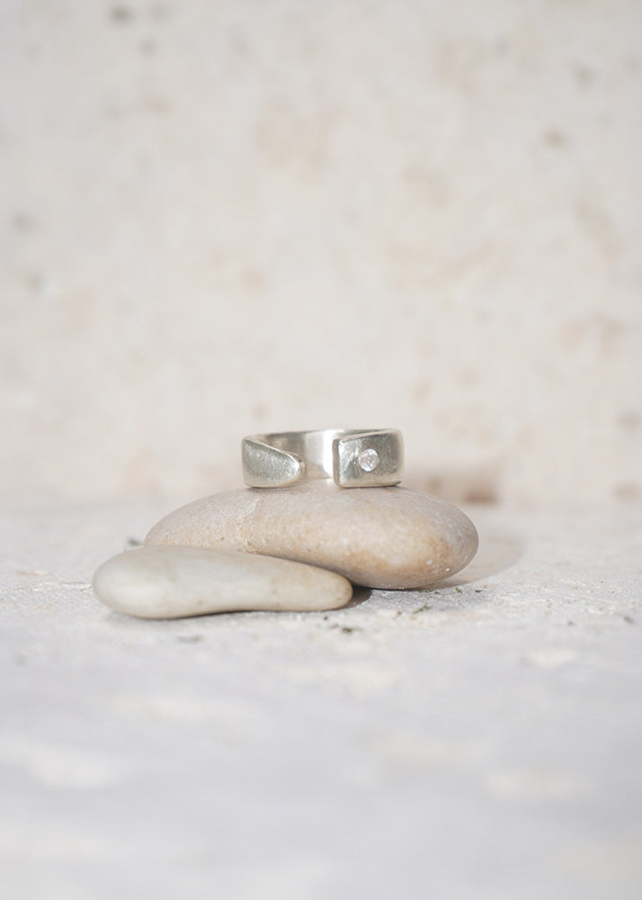 Silver ring on a stack of stones with a blurred natural background