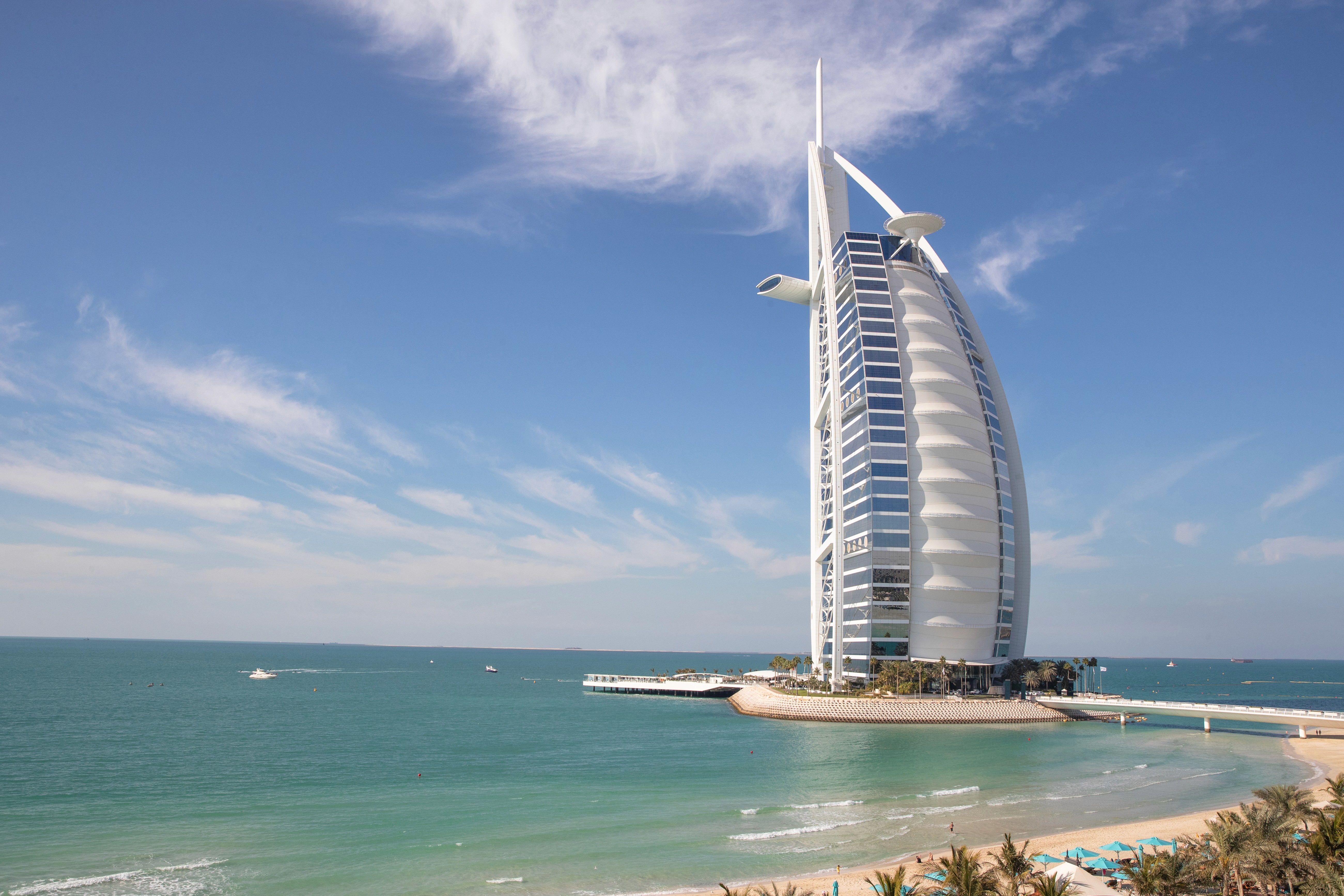 The Burj Al Arab is surrounded by the calm sea and the sunny beach views.